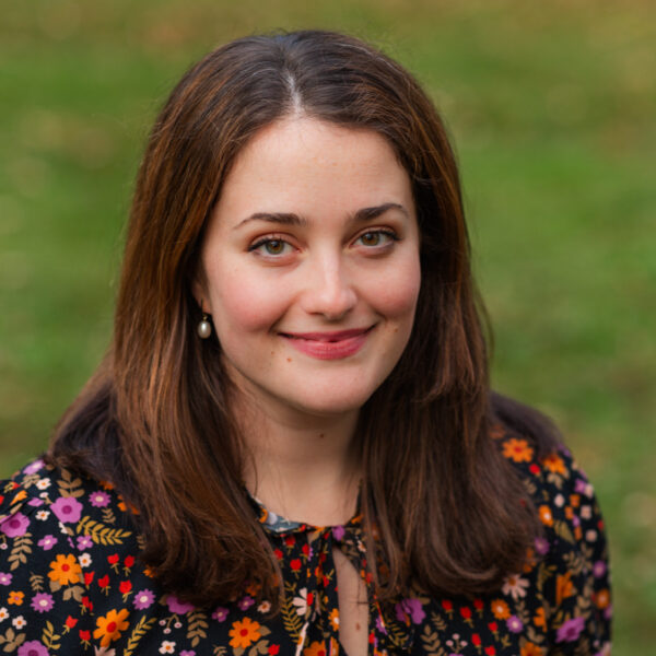 Hannah, outdoors, smiling, wearing floral patterned top with black background