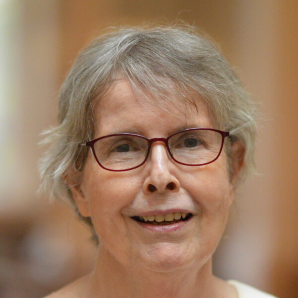 Mary Ellen Bowden, wearing glasses, smiling, blurred background