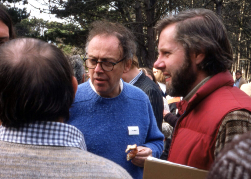 Three men talk amid a crowd outside